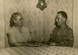 Photo of Bertha Bence and her son Raymond Everett Bence Jr. sitting at her kitchen table, summer 1945.
